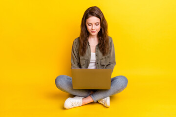 Photo of pretty adorable young woman dressed brown shirt sitting floor typing modern device isolated yellow color background