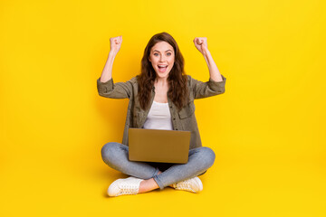 Full length portrait of pretty positive girl sit fists up open mouth achievement isolated on yellow color background