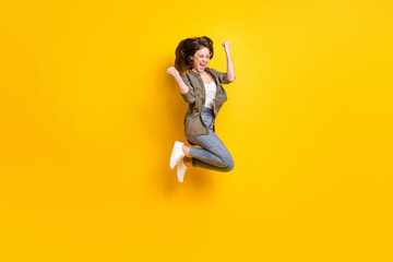 Fototapeta na wymiar Full length body size view of attractive cheerful lucky girl jumping rejoicing success isolated over bright yellow color background