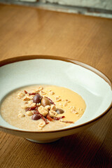 Amaranth porridge with cheese sauce and nuts in a white plate on a wooden background
