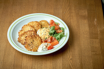 Fried potato pancakes with poached egg and lightly salted salmon. Hashbrown, dranik