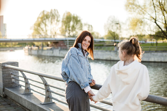 Smiling mother holding daughter's hand at embankment