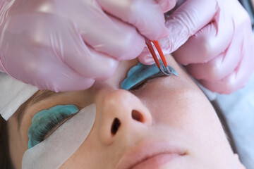 Lash lamination procedure cosmetologist separating the upper and lower eyelashes using tweezers....