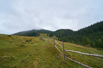Fototapeta na wymiar Wooden fence for cattle in the mountains. Mountain foggy background