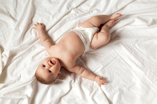 newborn baby in a diaper is lying on his back on a white sheet. products for children, toy. concept of a happy childhood and motherhood. child care. space for text. High quality photo