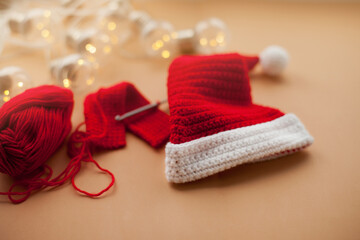 Crocheting a santa hat of red and white yarn on beige background for christmas gift