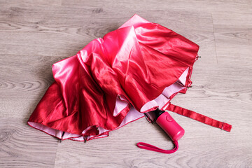 Folded bright pink umbrella on wooden table © Vera Aksionava