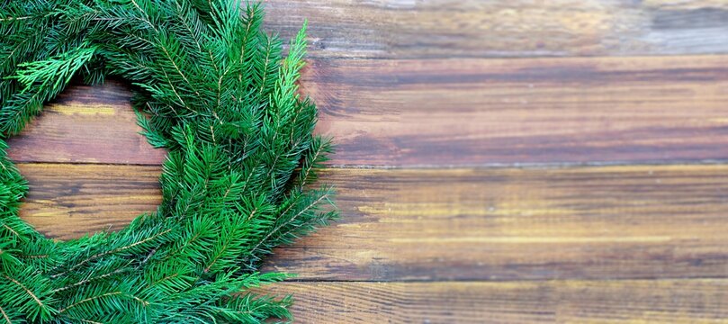 Christmas banner, undecorated evergreen wreath on rustic wooden background with copy space