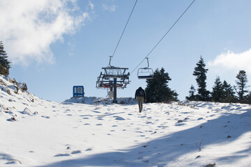 Fototapeta na wymiar Man walking at snow-capped mountain peak and sunny day
