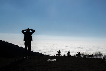 man looking to the horizon above the clouds and sunny day