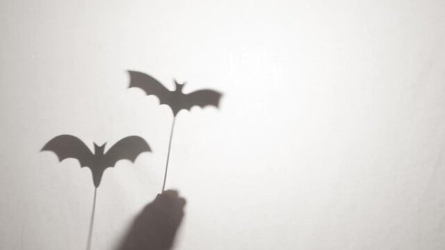 Halloween vampire bat shadow puppets silhouetted on sticks behind a white sheet
