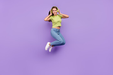 Fototapeta na wymiar Full length body size view of pretty cheery girl jumping listening hit melody having fun isolated over purple violet color background