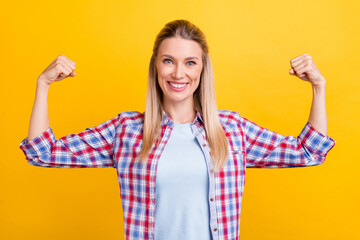 Photo of strong blond young lady show biceps wear plaid shirt isolated on yellow color background