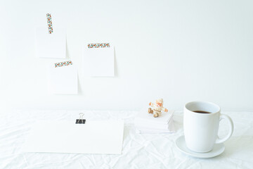 Obraz na płótnie Canvas Christmas or New Year breakfast scene. Notepad mockup of good intentions. Blank note paper hanging on the wall. Coffee cup,Santa Claus, empty paper sheet on the desk.Working space, home office concept