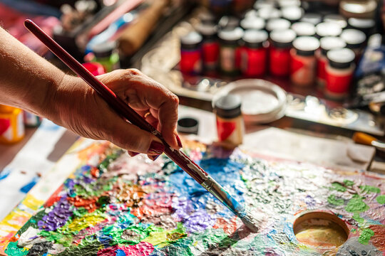 Woman mixing paint with brush on palette