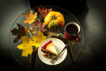 Cup of tea, pumpkin, leaves and cake on the table, dark background. Autumn concept.