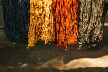 Multi colored threads hanging on bamboo. Hanging skeins of yarn background.