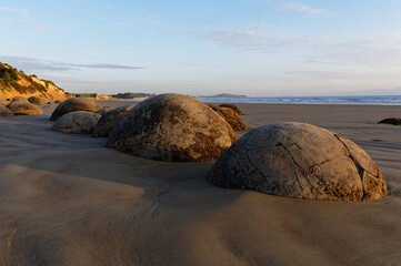 A line of Moeraki Boulders sit on the beach in New Zealand's South Island.