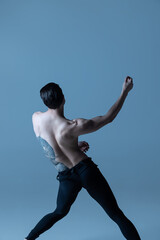 Obraz premium Back view of of young man, flexible male ballet dancer dancing isolated on old navy studio background. Art, motion, inspiration concept.