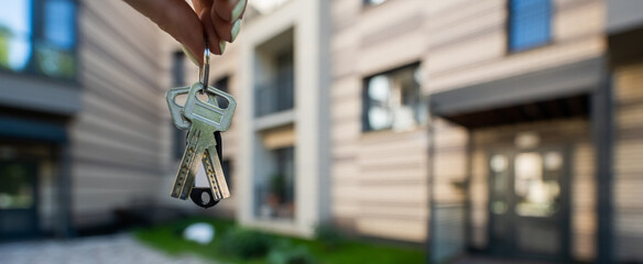 A woman holds the keys to a new house. Close-up of a female hand. Buying a property.