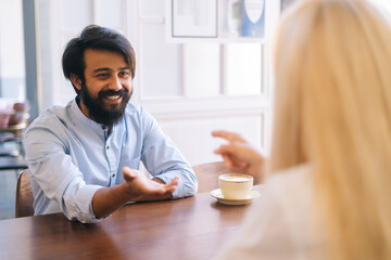 Close-up view from back of unrecognizable blonde young woman handshaking with cheerful bearded young business man closing deal at business meeting, job interview, agreement business.