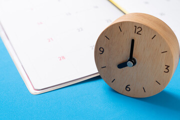 Fototapeta na wymiar close up of clock and calendar on the blue table background, planning for business meeting or travel planning concept