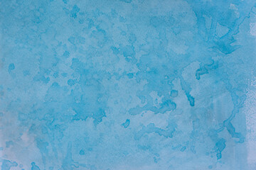 Blue watercolor background with drops. Handmade, splattered with a brush. Beautiful original streaks, imitation of the river, clouds. Vintage paper texture. Winter watercolor art background with spots