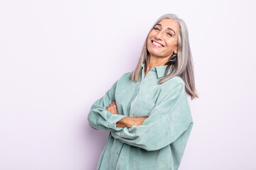 middle age gray hair woman laughing happily with arms crossed, with a relaxed, positive and...