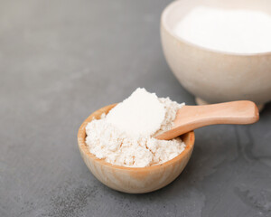 coconut flour in a wooden plate and a spoon. alternative flour for keto meal and LCHF diet. ingredient for healthy gluten free baking.