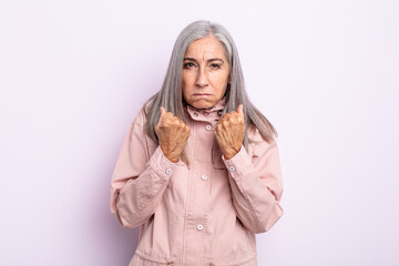middle age gray hair woman looking confident, angry, strong and aggressive, with fists ready to...