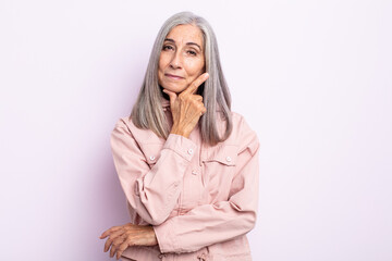 middle age gray hair woman looking serious, thoughtful and distrustful, with one arm crossed and...
