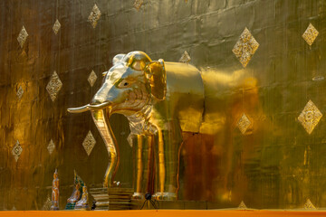 Golden elephant sculpture at the base of the main stupa inside compound of famous Lanna landmark Wat Phra Singh buddhist temple, Chiang Mai, Thailand