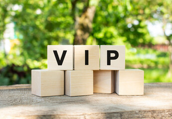 Three wooden cubes are stacked in the VIP word. They lie on other cubes against the backdrop of the summer garden.