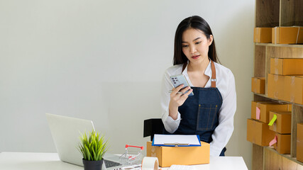 Portrait of a Small Business Startup, SME Owner, Asian Female Entrepreneur Work on receipt boxes and check online orders to prepare the boxes. Selling to customers. Online SME business idea.