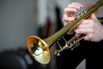 A person all in black playing a lacquered piston trumpet