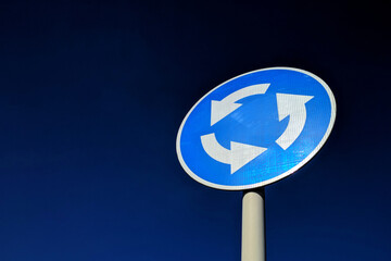 Roundabout road sign in blue on a blue sky background