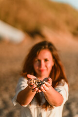 A woman holds beautiful pebbles from the beach in her hands