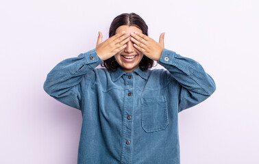 pretty teenager woman smiling and feeling happy, covering eyes with both hands and waiting for...