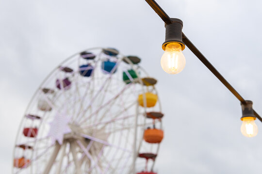 Glowing lamps against Ferris wheel