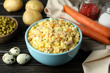 Olivier salad and ingredients on wooden background