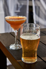 Mug of beer and glass with cocktail on the table