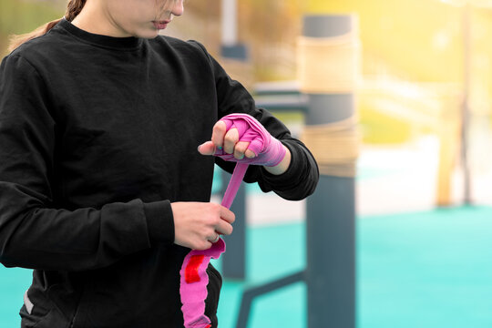 girl wrapping a wrist wrap around her hand before outdoor martial arts training - Powered by Adobe
