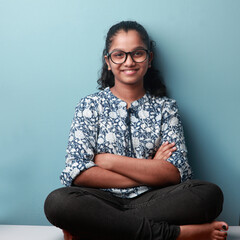 Happy smiling young girl of Indian ethnicity sitting in lotus pose 