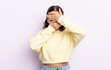 pretty teenager woman covering face with both hands saying no to the camera! refusing pictures or...