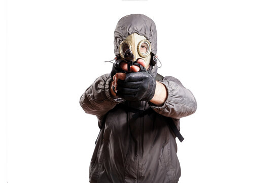 An isolated shot of a man dressed in a gas mask, a hooded jacket, a backpack, gloves, holding a gun and aiming straight. On a white isolated background
