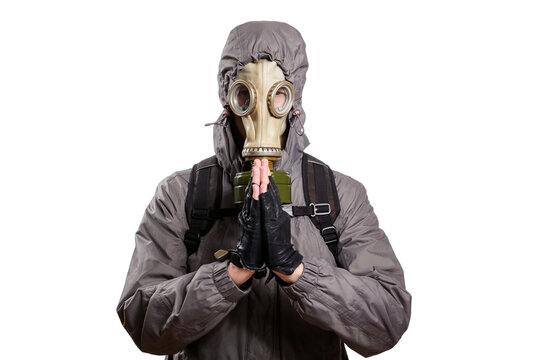 An isolated shot of a man dressed in a gas mask, a jacket with a hood, a backpack, praying, pressed the palms of his hands against each other. On a white isolated background
