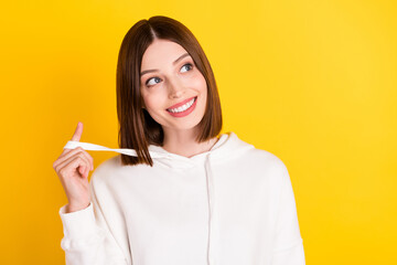 Photo of cheerful curious lady look empty space think thoughts wear white sweatshirt isolated yellow color background