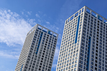 Fototapeta na wymiar View of modern buildings against a blue sky with white clouds from an unusual angle