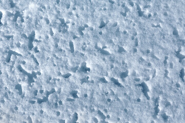 Texture and pattern of a snowy surface with deep dimples from fallen ice. Natural snow background. Top view.