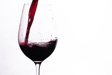 Glass of red wine. Red alcohol pouring in a glass. Splash of red wine.
